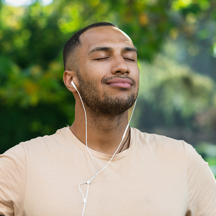 Close Up Portrait Of Sportsman In Park, Hispanic Man Jogging In Park With Eyes Closed Breathing Fresh Air And Resting, Jogging With Headphones Listening To Music And Online Radio And Podcasts